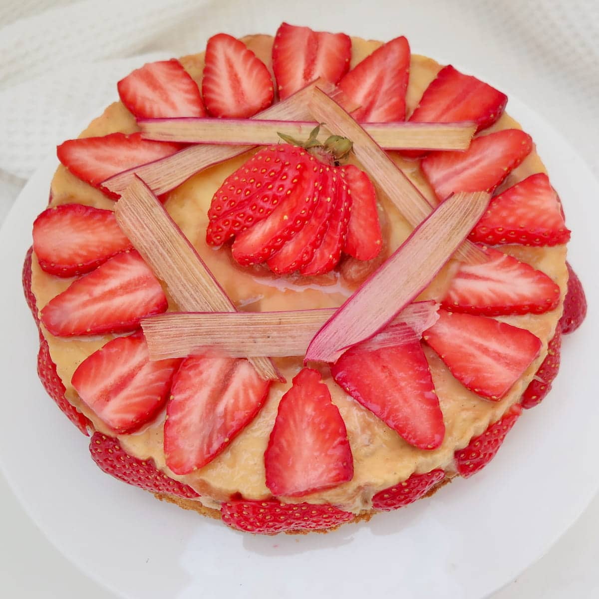rhubarb and custard cheesecake, decorated with rhubarb chips and strawberries