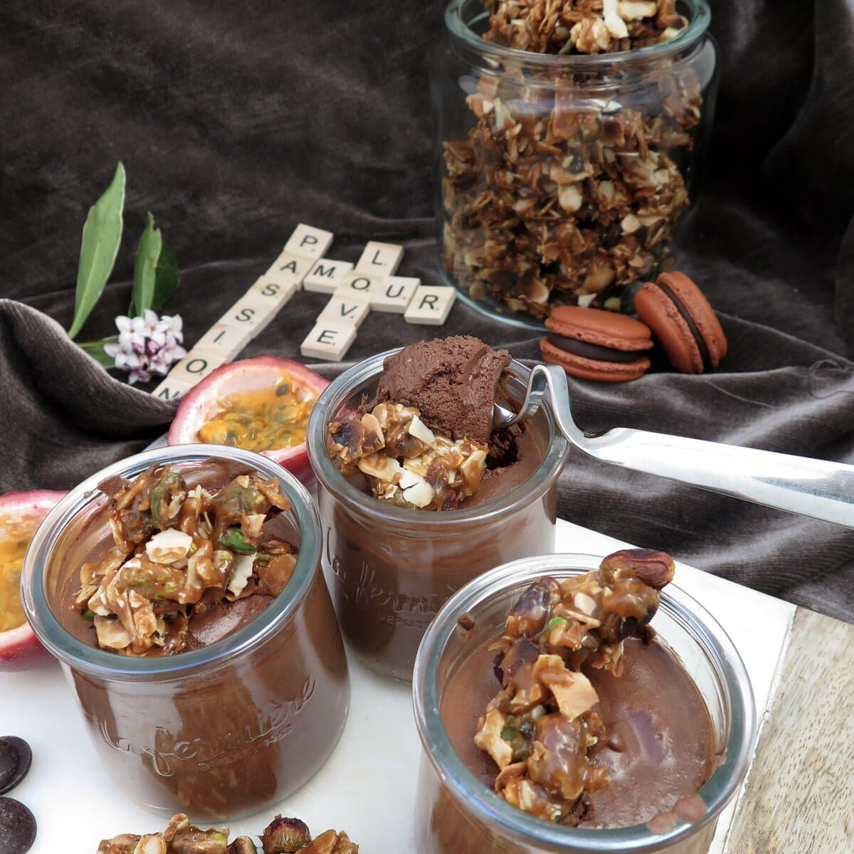 glass pots of chocolate mousse topped with nutty caramel, passion fruits, macarons and scrabble letters for amour